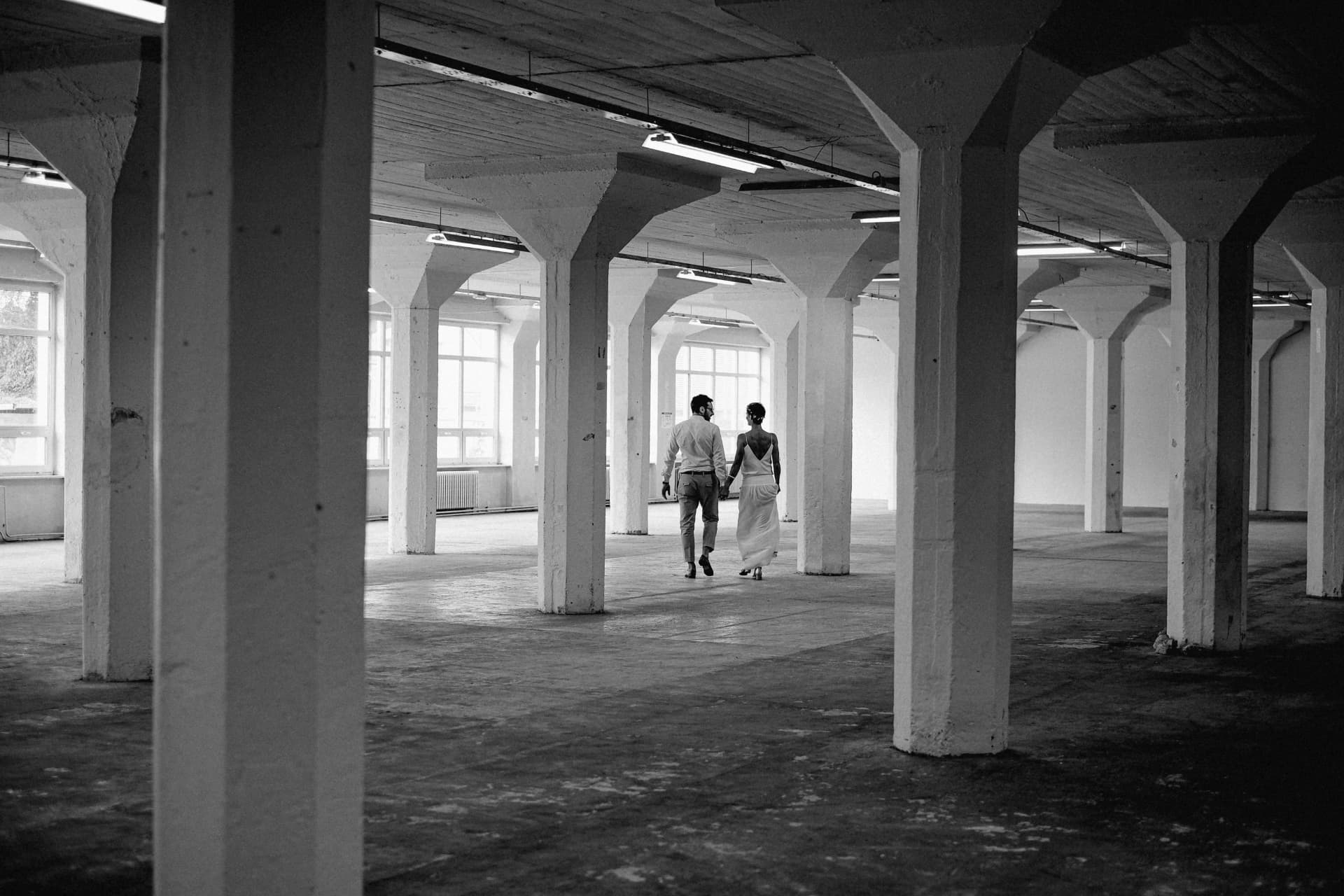 Newlyweds walking through an industrial hall