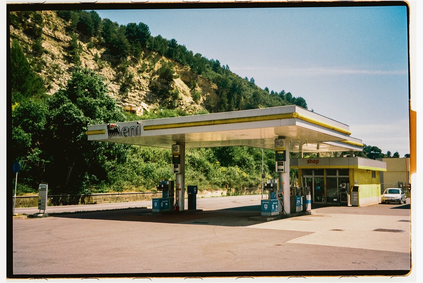 Roadside Eni petrol station beneath a wooded hillside