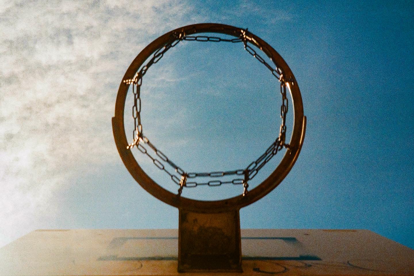 Basketball hoop viewed from below against a blue sky
