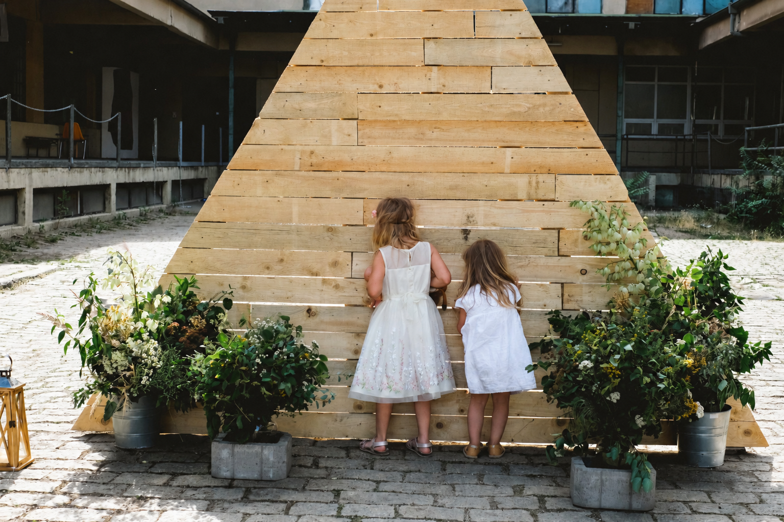 Two children standing by the wooden wedding backdrop