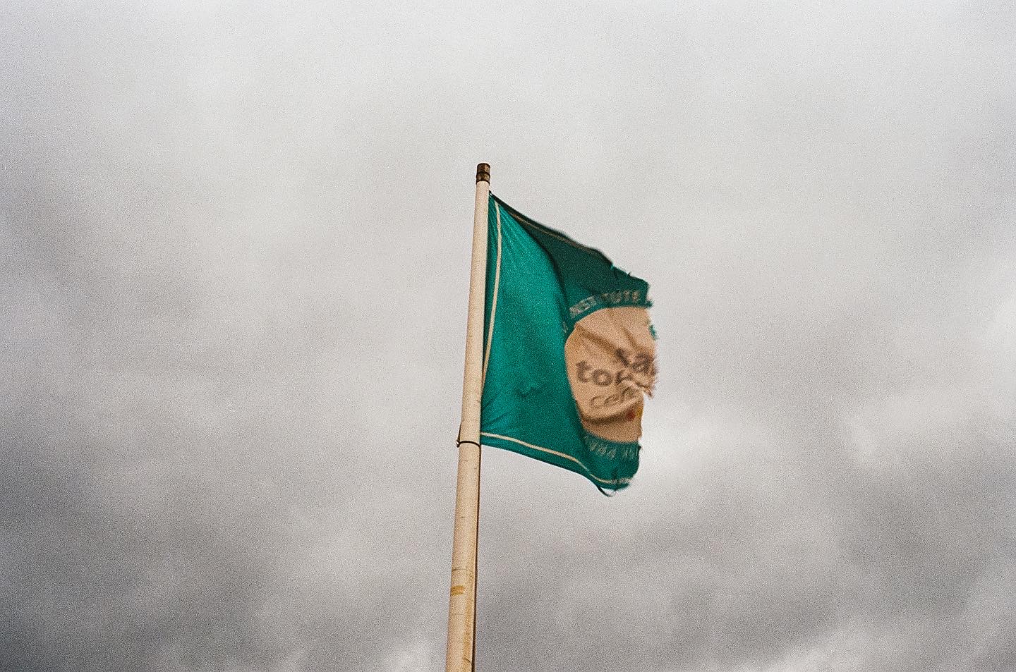 Torn green flag beneath an overcast sky