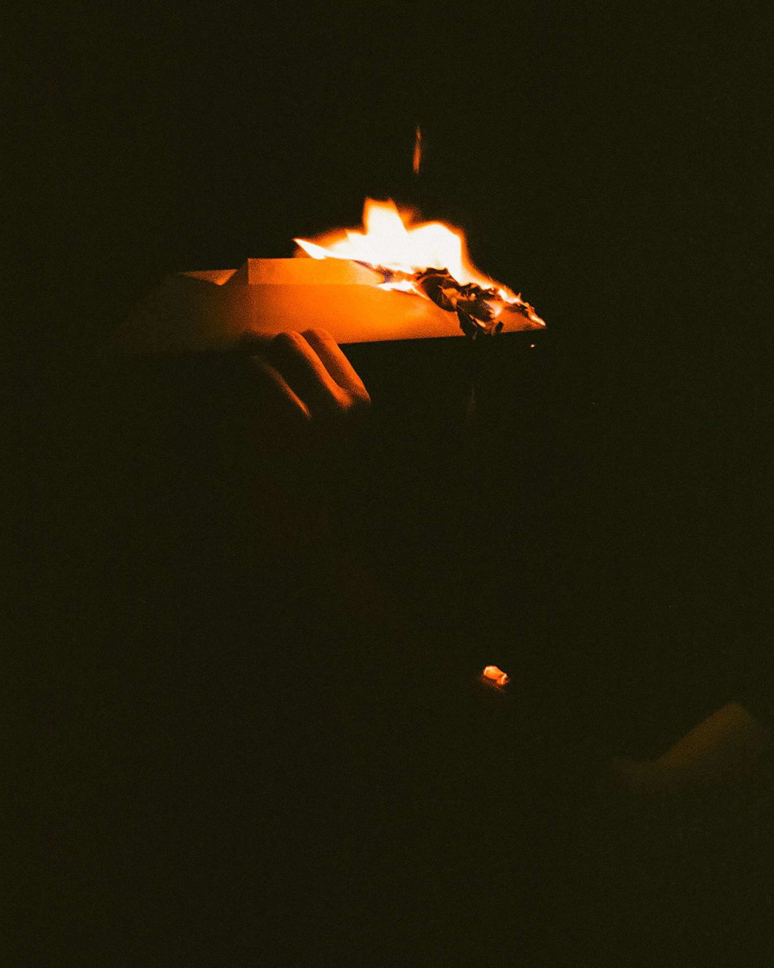 Hands holding burning paper in the dark