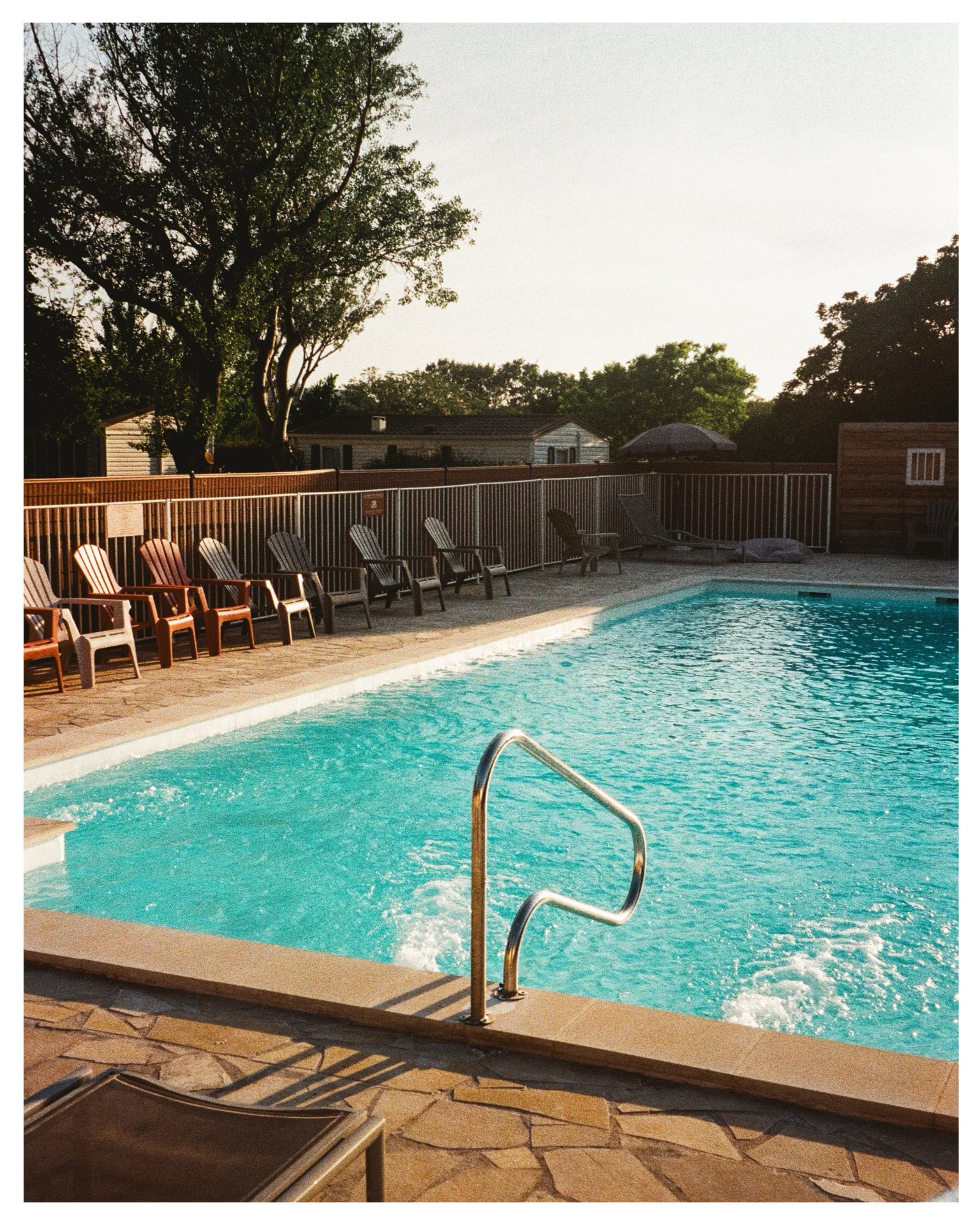 Sunlit swimming pool with empty chairs