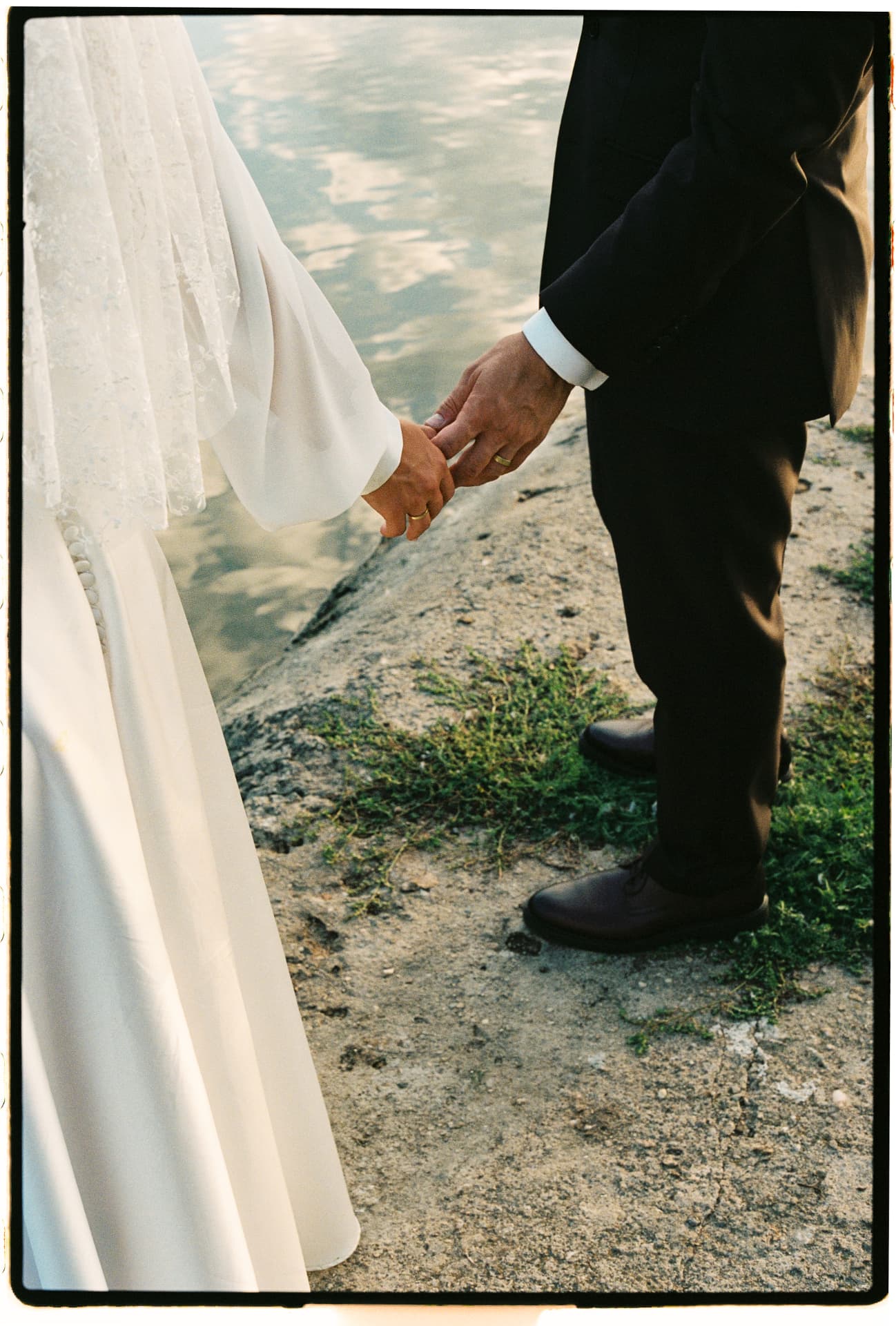 Bride and groom holding hands by the water
